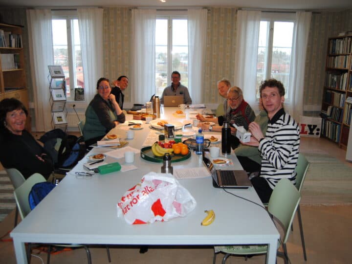 8 personer sitter runt ett bord i en konferenslokal